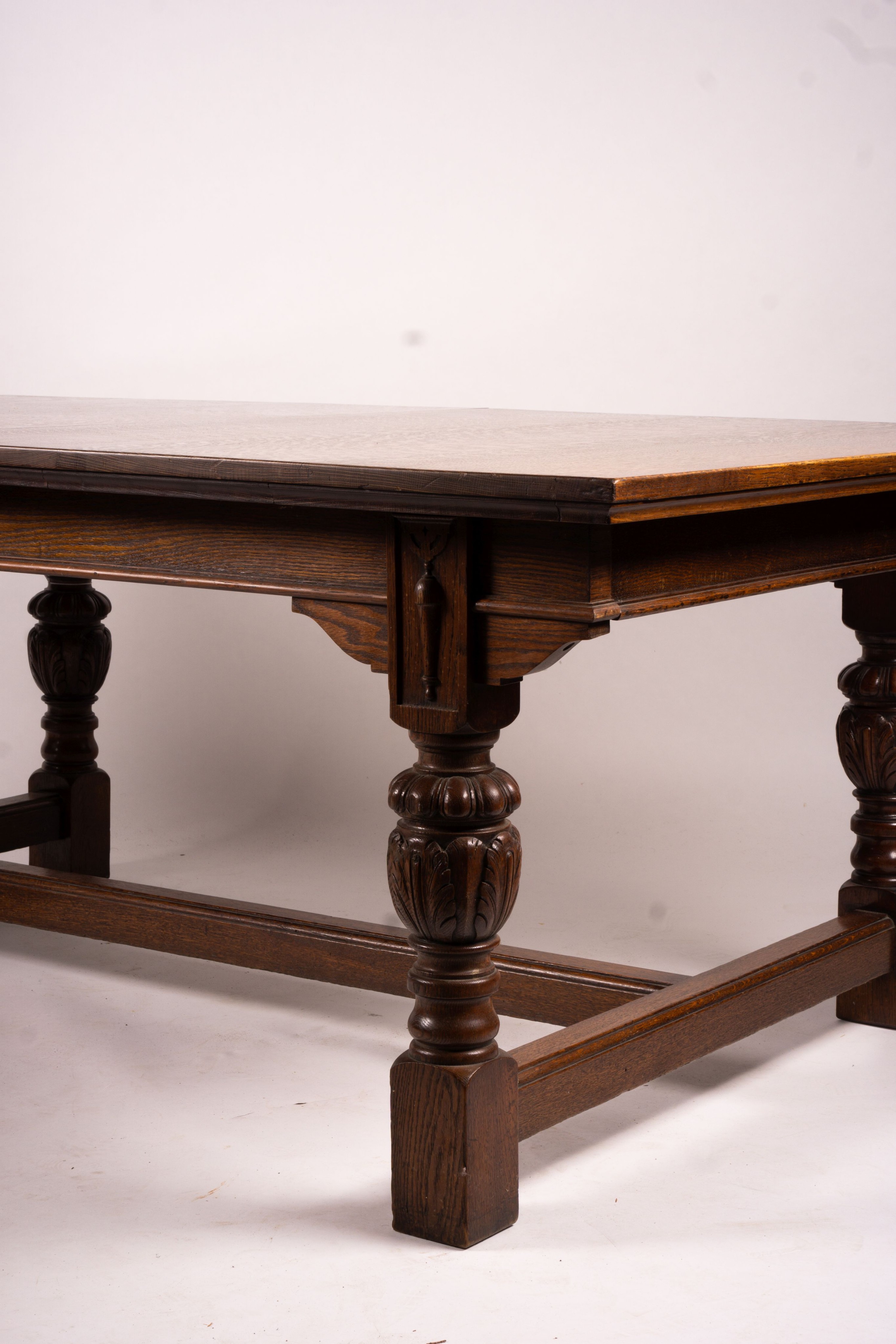 A 17th century style carved rectangular oak extending dining table with 'H' stretcher, 300cm extended, two spare leaves, width 121cm, height 75cm